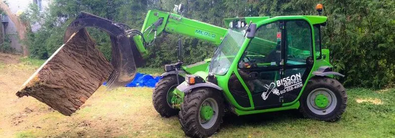 Telehandler carrying a large log section across a lawn